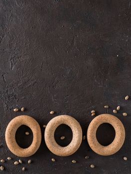 Ring-shaped cracknel with whole grain hemp seed flour and hemp seeds on black background. ring-shaped cracknel close up. Copy space Top view or flat lay. Vertical.