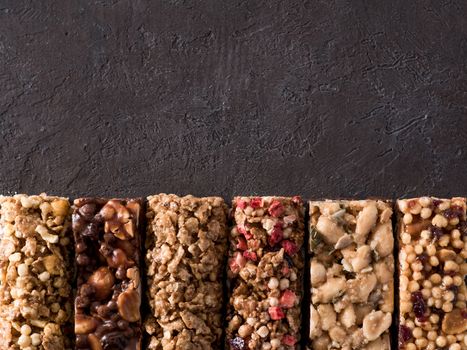 Granola bar with copy space. Set of different granola bars on black background. Shallow DOF. Top view or flat lay.