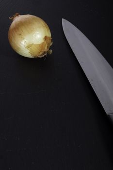 Ripe onion in husk on a black stone cutting board