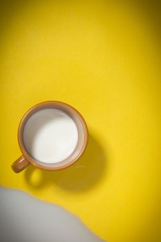 Cup with milk on a yellow background