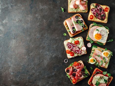 Set of eight different sandwiches with meat, copy space for design or text. Top view or flat lay. Assortment meat toasts on black background. Idea, creative concept for sausage maker