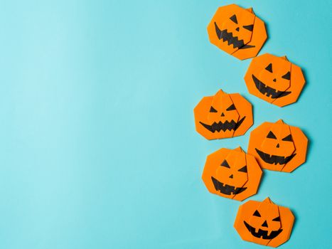 Halloween concept. Paper origami pumpkin on bright blue background. Simple idea for halloween - easy made paper pumpkins on light blue color background. Copy space for text.