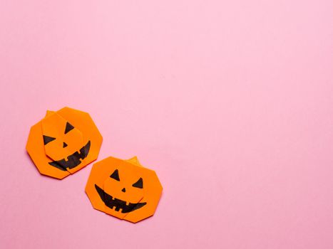 Halloween concept. Paper origami pumpkin on pink background. Simple idea for halloween - easy made paper pumpkins on trendy color Ceylon Yellow background. Copy space for text.