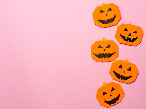 Halloween concept. Paper origami pumpkin on pink background. Simple idea for halloween - easy made paper pumpkins on trendy color Ceylon Yellow background. Copy space for text.