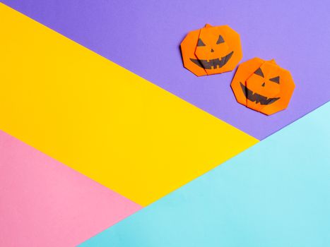 Halloween concept. Paper origami pumpkin on colorful background. Simple idea for halloween - easy made paper pumpkins on multicolor background. Copy space for text.