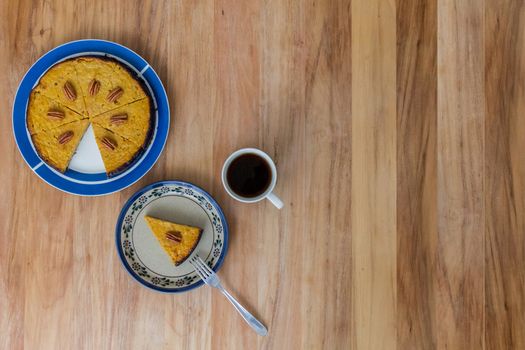 Walnut and pumpkin pie with coffee on a light wooden surface