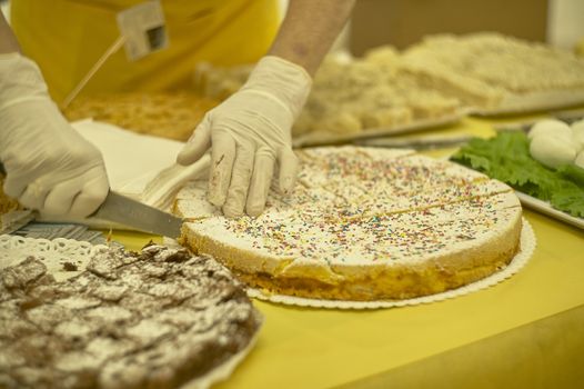 Cake covered with velvety sugar and colored sugars while sliced into a tasting stand in a market of typical Italian products.