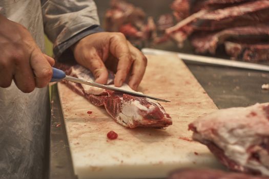 Butcher trying to pull or cut a piece of calf in a butcher shop.