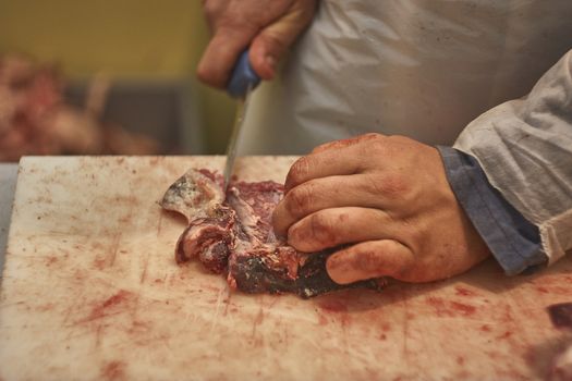 butcher who slices a steak in his butcher to prepare it for sale