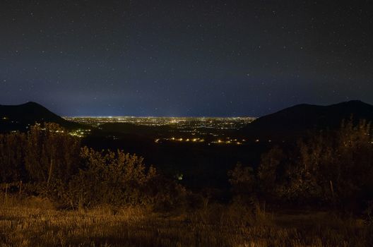 Hilly landscape of northern Italy, Precisely of Este in Veneto. Very impressive night landscape where you can see the hills at the sides and the lights of the city that are lost in the sky below a starry sky.