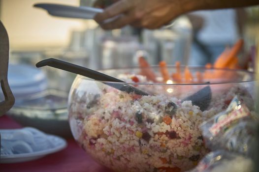 Bowl full of rice salad resting on the table during an aperitif to satisfy the hunger of the banqueting. Typical dish of Italian cuisine.