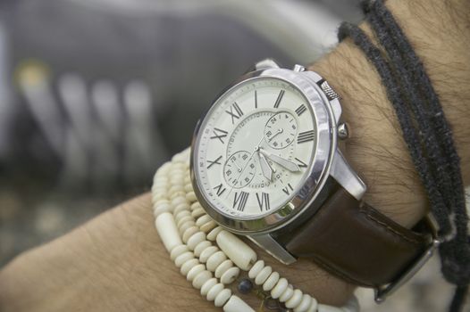 Detail of a vintage wristwatch worn by a boy with other bracelets, symbol of time passing. A great acession for a perfect outfit.