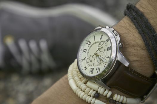  Detail of a vintage wristwatch worn by a boy with other bracelets, symbol of time passing. A great acession for a perfect outfit.