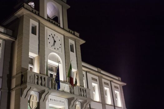 Front view of an Italian town hall (Porto Viro) in Veneto, resumed at night with lit lights.