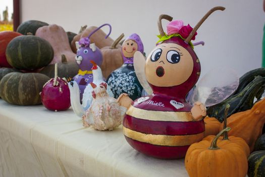 Stall at a marketplace containing small handicraft sculptures in the form of various animals made with pumpkins.