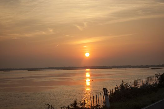 Magnificent dawn on the delta of the Po River in Italy, with the sun rising in the center of the photo.