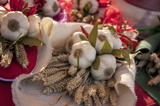 Heads of garlic and wheat and chillies in a decorative composition with food to embellish a stall of a fruit and vegetable market.