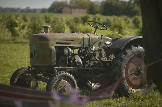 Old rusty and ruined agricultural tractor from work hours made over the last 50 years. Symbol of working life in the fields.