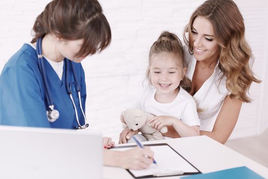 Young pediatrician doctor talking with girl and her mother