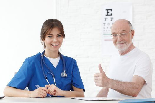 Happy senior patient with new glasses in ophthalmologist office