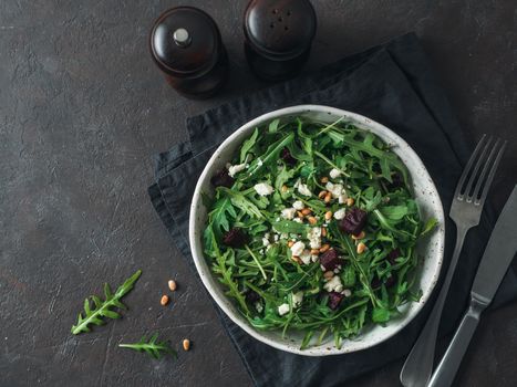 Beetroot, aragula and soft cheese salad over black background. Top view or flat lay. Copy space for text. Idea and recipe for healthy vegetarian salad. Clean eating diet concept