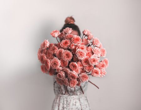 Bouquet in female hands. Bunch of Living Coral roses. Color of year 2019 Living Coral concept.