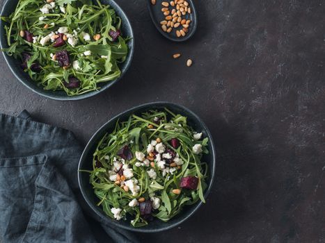 Beetroot, aragula and soft cheese salad over black background. Top view or flat lay. Copy space for text. Idea and recipe for healthy vegetarian salad. Clean eating diet concept