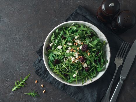 Beetroot, aragula and soft cheese salad over black background. Top view or flat lay. Copy space for text. Idea and recipe for healthy vegetarian salad. Clean eating diet concept