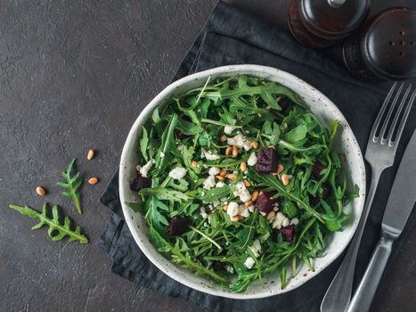 Beetroot, aragula and soft cheese salad over black background. Top view or flat lay. Copy space for text. Idea and recipe for healthy vegetarian salad. Clean eating diet concept