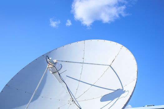 Big parabolic satellite antenna for telecommunications on a background of blue sky.