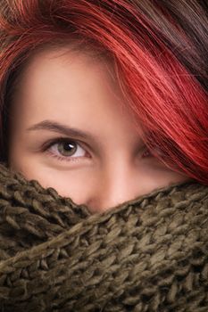 Under the comfort and softness of winter clothes. Close up shot of a beautiful young girl wrapped in a soft and comfy green woolen scarf.