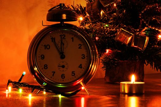 Almost time for celebration. A close up shot of an old clock with candles, Christmas lights and Christmas tree in the background.