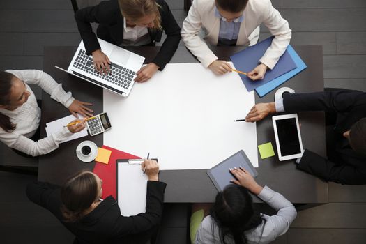 Business workplace with people, cup of coffee, digital tablet, smartphone, papers and various office objects on table
