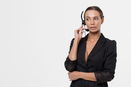 Isolated attractive sexy woman in black opened costume with hand on belt holding headphone's micro and looking away