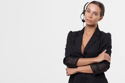 Isolated attractive sexy woman in black opened costume with hand on belt holding headphone's micro and looking away