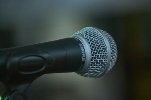 Detail of a microphone for singing taken in front view (view of the singer) with the background completely blurred. Useful as a graphical resource.