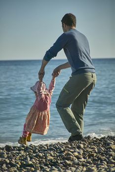 Father and daughter intent on playing together and lovingly on the shore of the sea. Children's memories and memories