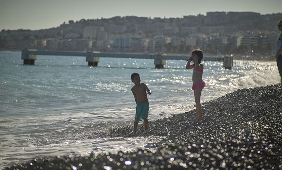 Pair of playing kids having fun on Nice beach at sunset.