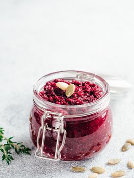 Beetroot pesto or hummus. Homemade beet pesto sauce in glass jar and fresh thyme on dark black background. Copy space for text. Ideas and recipes for healthy vegetarian detox diet food