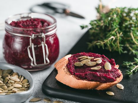 Beetroot pesto or hummus. Homemade beet pesto sauce in glass jar and fresh thyme on dark black background. Copy space for text. Ideas and recipes for healthy vegetarian detox diet food