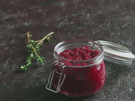 Beetroot pesto or hummus. Homemade beet pesto sauce in glass jar and fresh thyme on dark black background. Copy space for text. Ideas and recipes for healthy vegetarian detox diet food