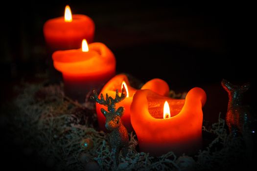 Christmas candles in advent with snowy decor on dark background