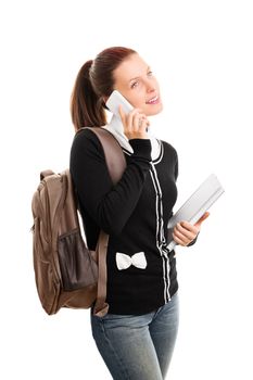 Beautiful smiling young student girl with a backpack, holding books and talking on a phone, isolated on white background.