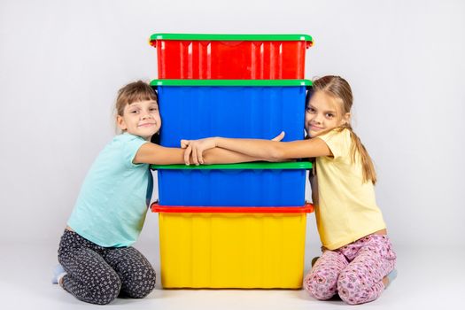 Two girls hug big plastic boxes