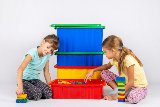 Two girls opened a box with a designer and start to play toys