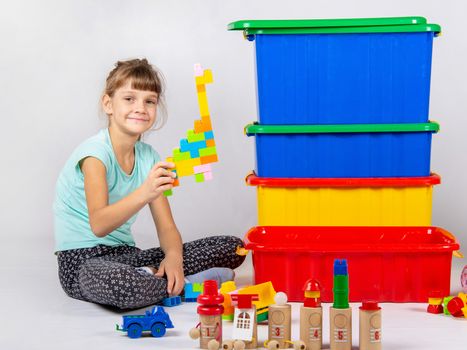 Girl playing toys, large plastic boxes are standing nearby
