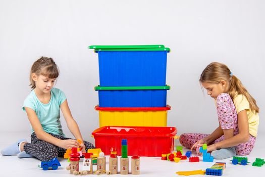 Two girls play toys, in the middle are boxes with toys