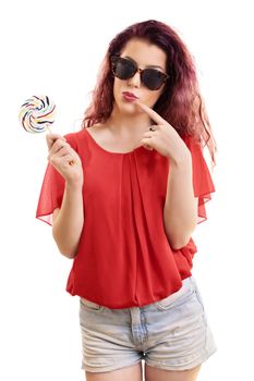 Beautiful young redhead girl with sunglasses holding a colorful lollipop, isolated on white background.