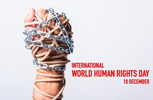 Rope and chain on fist hand with international world HUMAN RIGHTS DAY 10 december text on white background, Human rights day concept