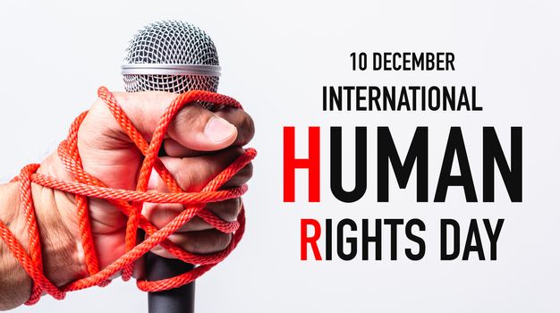 Hand holding microphone and have roped on fist hand with 10 december international HUMAN RIGHTS DAY text on white background, Human rights day concept